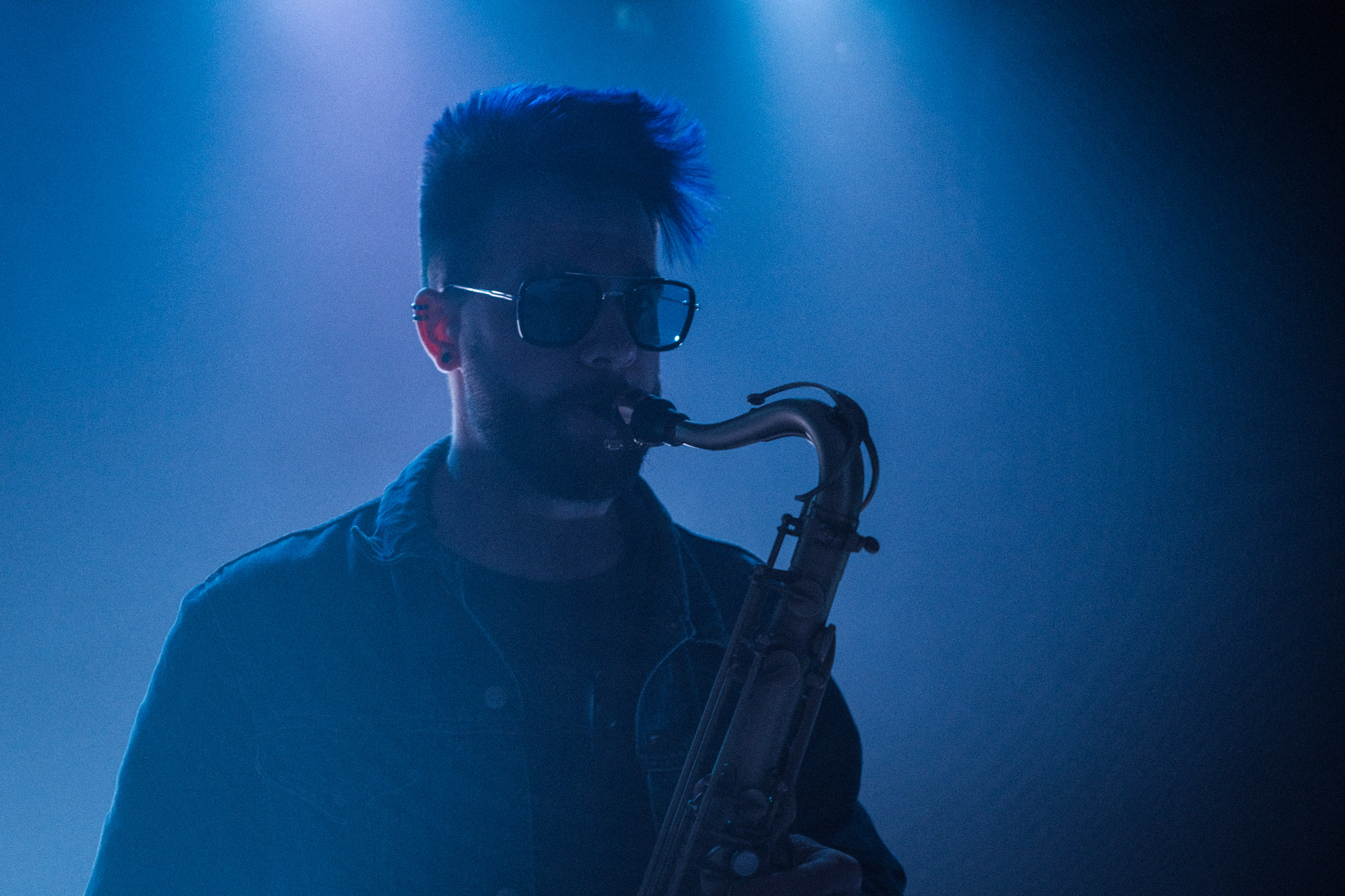Lucas Sanor playing saxophone in blue stage light